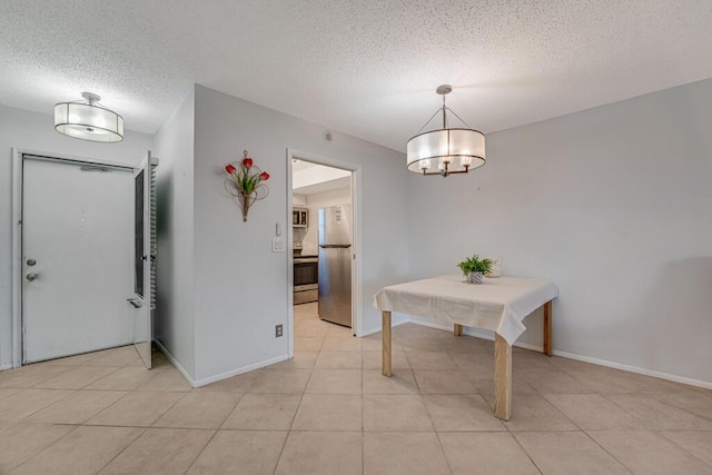 dining space featuring a textured ceiling, baseboards, light tile patterned floors, and a chandelier