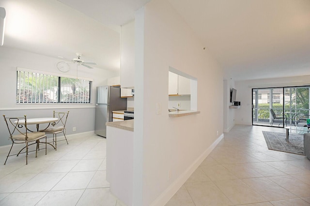 corridor featuring light tile patterned flooring, baseboards, and vaulted ceiling