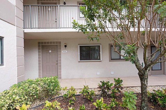 doorway to property with a balcony and stucco siding
