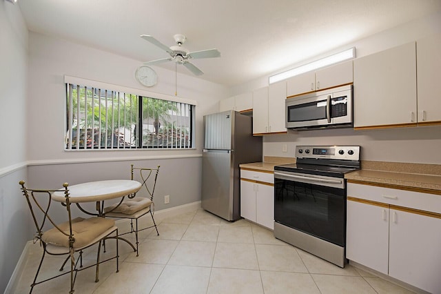 kitchen with stainless steel appliances, a ceiling fan, light tile patterned floors, light countertops, and baseboards