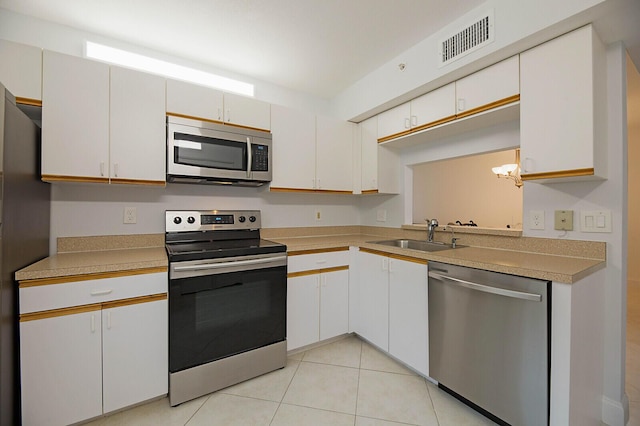kitchen with appliances with stainless steel finishes, a sink, light countertops, and light tile patterned flooring