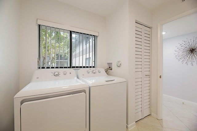 washroom with washing machine and clothes dryer, light tile patterned floors, and baseboards