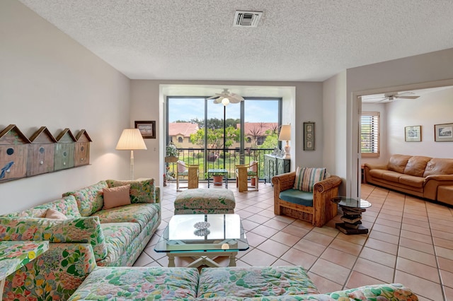 living room featuring light tile patterned floors, ceiling fan, and a textured ceiling