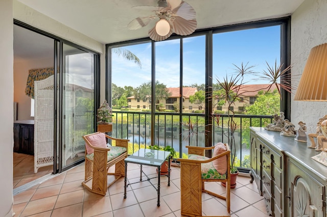 sunroom / solarium with floor to ceiling windows, healthy amount of natural light, a water view, tile patterned floors, and a residential view
