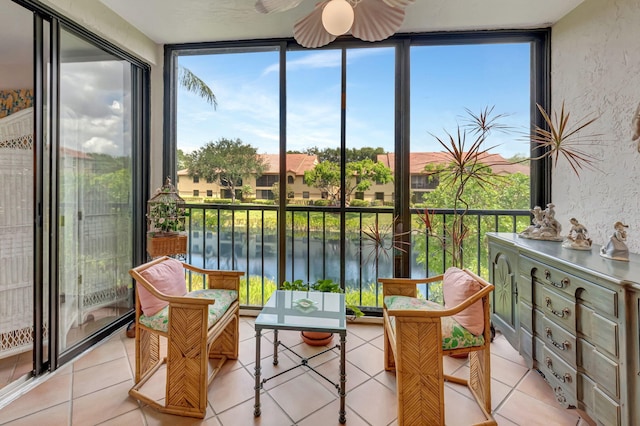 sunroom / solarium featuring expansive windows, a water view, tile patterned flooring, and a textured wall
