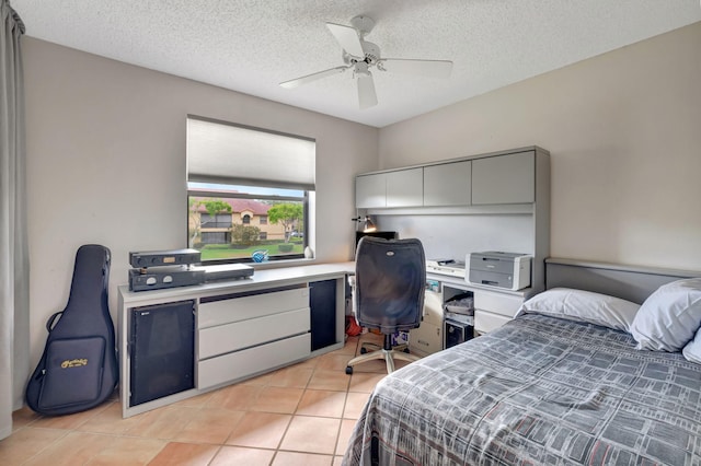 bedroom with an office area, light tile patterned floors, a textured ceiling, and a ceiling fan