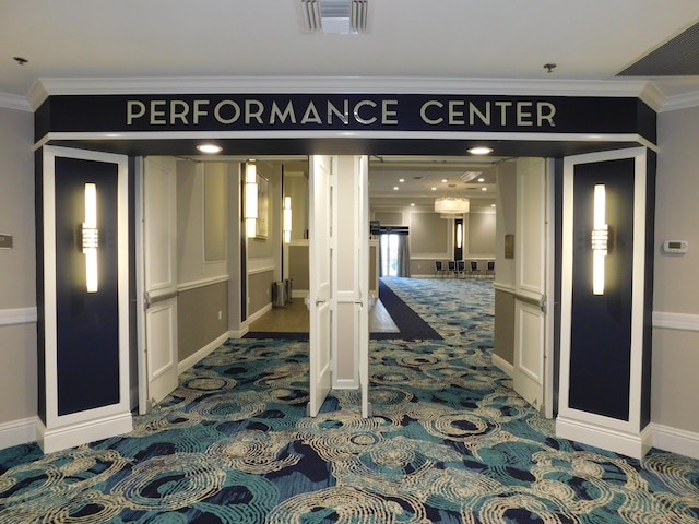 corridor with ornamental molding, dark colored carpet, and baseboards