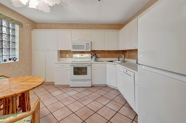 kitchen featuring white appliances, light countertops, a sink, white cabinetry, and a textured ceiling