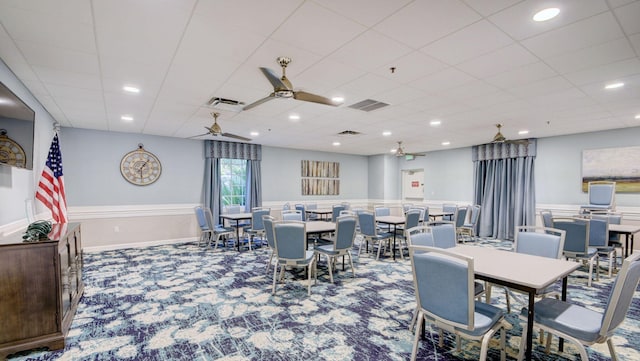 dining area featuring a ceiling fan, carpet flooring, and a paneled ceiling