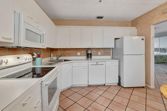 kitchen featuring white appliances, light countertops, a sink, white cabinets, and a textured ceiling