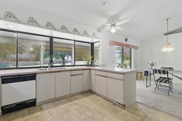 kitchen featuring white dishwasher, a sink, light countertops, light brown cabinetry, and hanging light fixtures