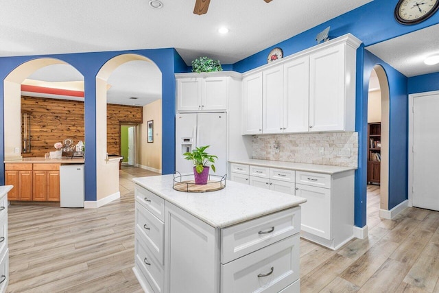 16737 Temple Blvd, Loxahatchee, FL 33470 - kitchen featuring white refrigerator with ice dispenser, arched walkways, ceiling fan, baseboards, and a textured ceiling