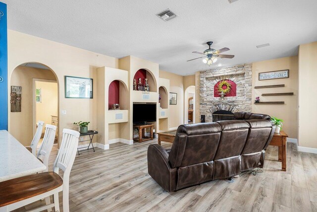 16737 Temple Blvd, Loxahatchee, FL 33470 - living room featuring ceiling fan, light wood finished floors, baseboards, arched walkways, and a fireplace