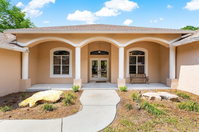 16737 Temple Blvd, Loxahatchee, FL 33470 - view of exterior entry featuring french doors, covered porch, stucco siding, and roof with shingles