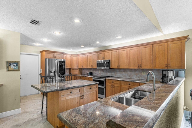 22075 Flower Dr, Boca Raton, FL 33428 - kitchen with appliances with stainless steel finishes, a sink, brown cabinets, a kitchen bar, and a center island