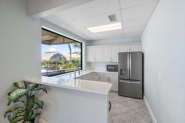 22075 Flower Dr, Boca Raton, FL 33428 - kitchen with stainless steel fridge with ice dispenser, light countertops, a paneled ceiling, white cabinetry, and a peninsula