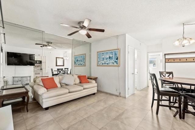 living room featuring a chandelier, a ceiling fan, a textured ceiling, light tile patterned floors, and baseboards