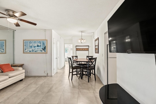 dining room with a ceiling fan, a chandelier, a textured ceiling, light tile patterned floors, and baseboards