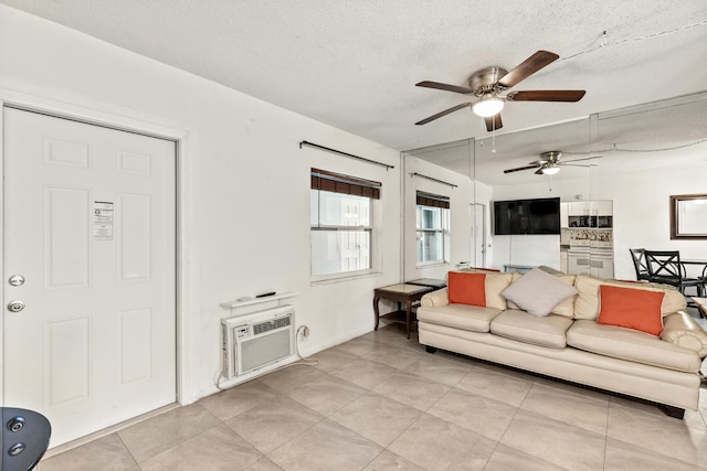 living area featuring a ceiling fan, light tile patterned flooring, a textured ceiling, and a wall mounted air conditioner