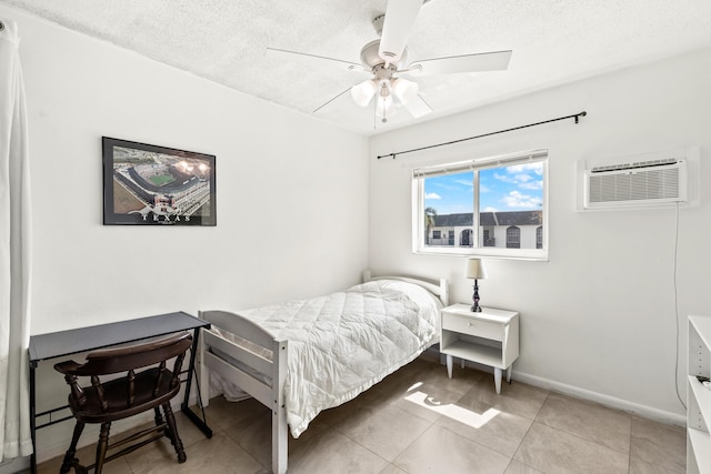 bedroom featuring a textured ceiling, a wall mounted air conditioner, light tile patterned floors, a ceiling fan, and baseboards