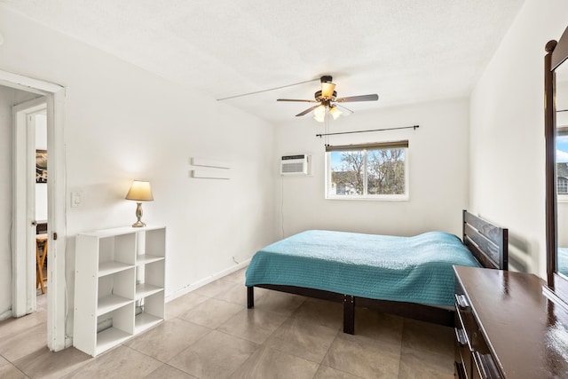 bedroom with a wall unit AC, light tile patterned floors, a ceiling fan, and baseboards