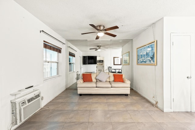 living room featuring ceiling fan, a textured ceiling, light tile patterned flooring, and a wall unit AC