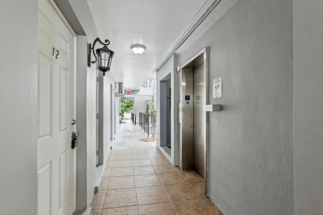 corridor with elevator and stone finish floors