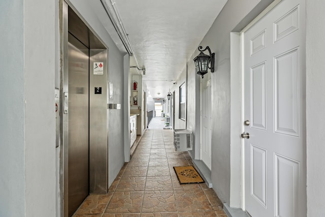 hall with stone tile floors and elevator
