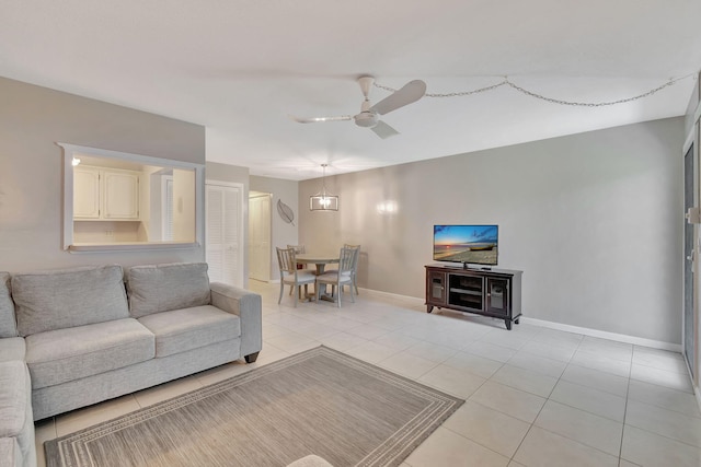 living area featuring ceiling fan, baseboards, and light tile patterned flooring