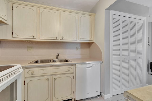 kitchen with white appliances, a sink, light countertops, light tile patterned floors, and cream cabinets