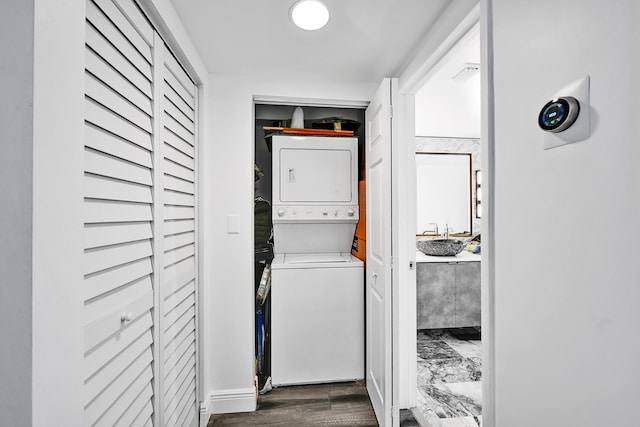 laundry room with stacked washer / dryer and dark wood-type flooring