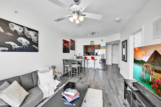 living area featuring wood finished floors, a textured ceiling, and ceiling fan