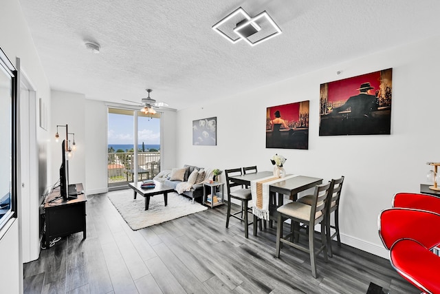 dining space with a textured ceiling, wood finished floors, a ceiling fan, and baseboards