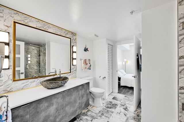 ensuite bathroom featuring marble look tile flooring, a stall shower, toilet, and vanity