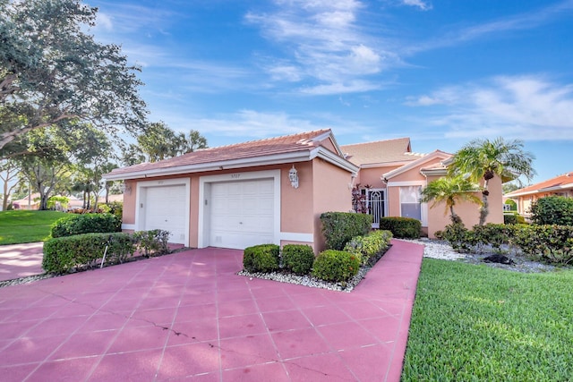 view of front of property with stucco siding, driveway, a tile roof, a front lawn, and a garage