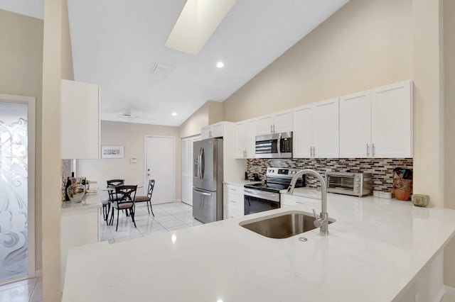 kitchen with appliances with stainless steel finishes, decorative backsplash, white cabinetry, a sink, and light countertops