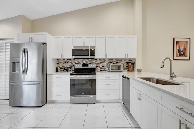 kitchen featuring stainless steel appliances, a sink, decorative backsplash, white cabinets, and light countertops