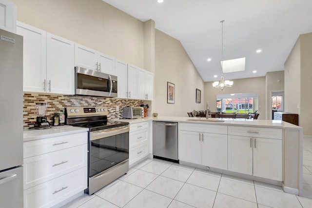 kitchen featuring stainless steel appliances, a sink, decorative backsplash, a chandelier, and vaulted ceiling