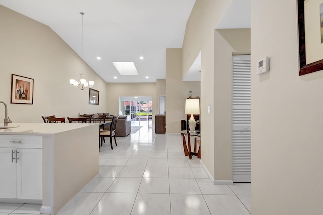 hallway featuring a chandelier, light tile patterned floors, a skylight, a sink, and lofted ceiling