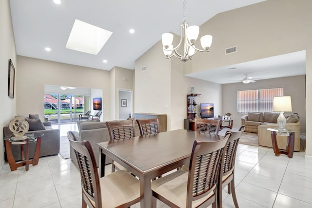 dining area with light tile patterned flooring, high vaulted ceiling, a chandelier, a skylight, and ceiling fan