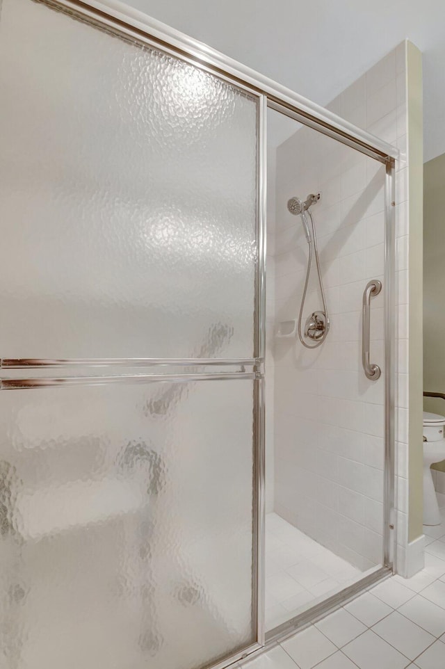 bathroom with a shower stall, tile patterned floors, and toilet