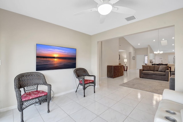 tiled living area featuring a chandelier, ceiling fan, vaulted ceiling, and baseboards
