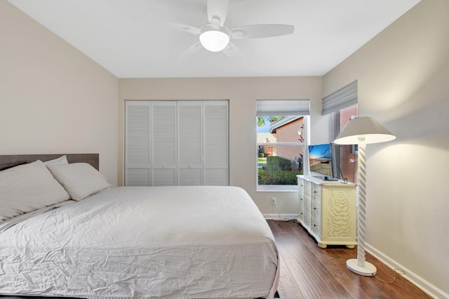 bedroom with dark wood-type flooring, baseboards, a closet, and a ceiling fan