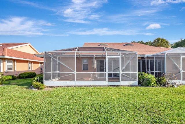 rear view of property featuring a lawn and a lanai