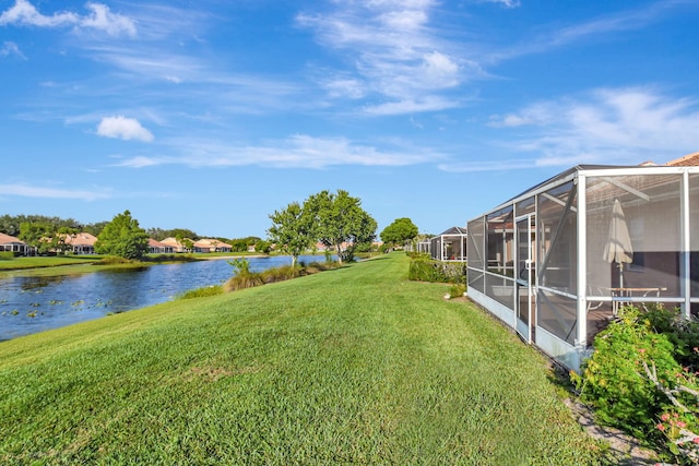 view of grassy yard featuring a water view, a residential view, and a lanai
