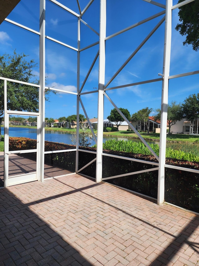 view of patio with a water view and a lanai