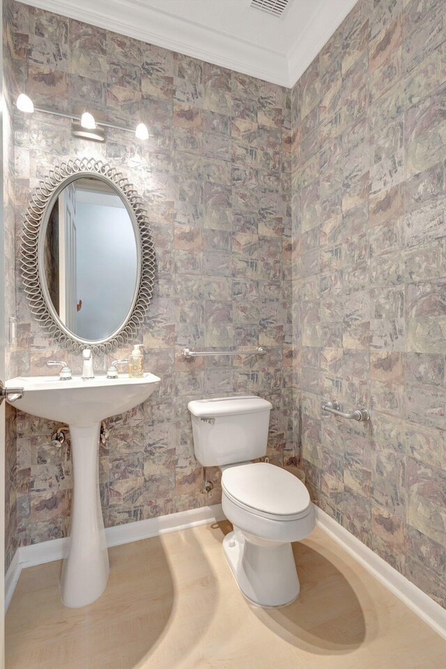 bathroom with ornamental molding, toilet, and baseboards