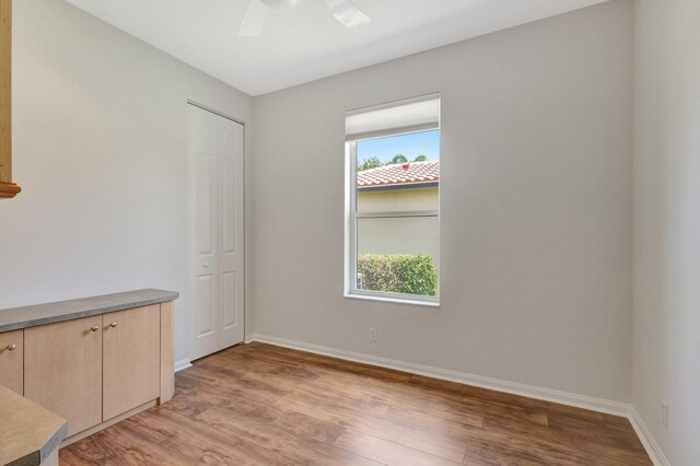 unfurnished room with light wood-type flooring, baseboards, and a ceiling fan