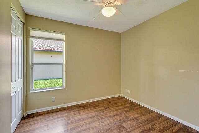 spare room featuring plenty of natural light, dark wood-style floors, ceiling fan, and baseboards