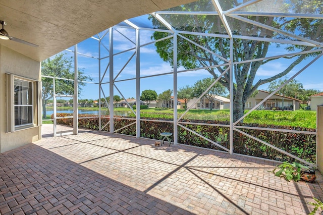 view of patio / terrace with a water view, glass enclosure, and ceiling fan